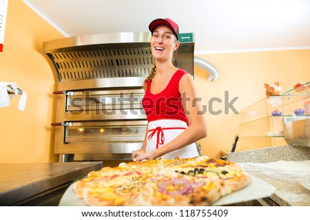Woman pushing the finished pizza from the oven with the pizza shovel