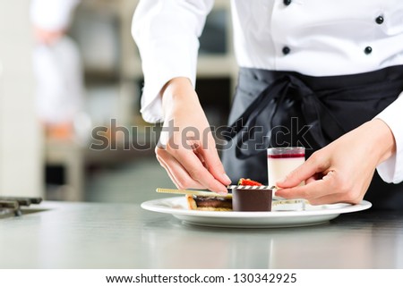 Cook, the female pastry chef, in hotel or restaurant kitchen cooking, she is finishing a sweet dessert