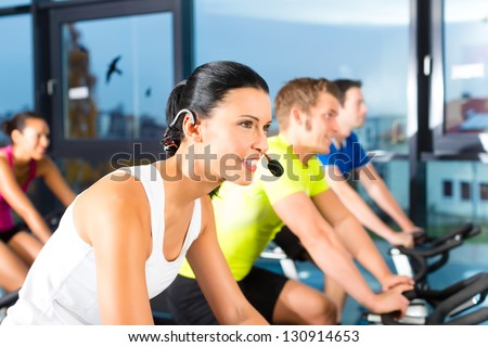 Young People - group of women and men - doing sport Spinning in the gym for fitness