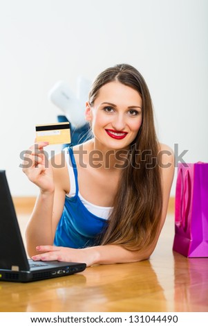 Young Woman buying on the Internet online using the laptop, she is paying with her golden Credit Card