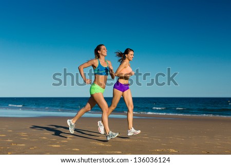 two women doing sport, jogging on the beach in their vacation on the sea