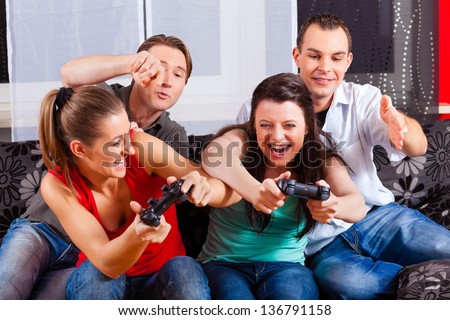 Friends - two couples - sitting in front of game console box and do have lots of fun
