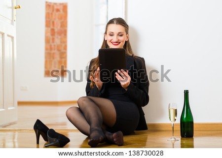 Online Dating - Young businesswoman sitting at home on the floor while using a tablet computer for online dating