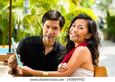 Asian man and woman in restaurant are selecting the food and are hungry