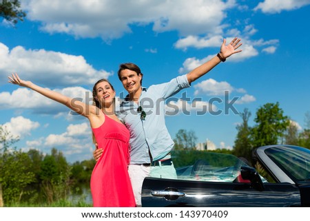 Young hip couple - man and woman - with cabriolet convertible car in summer on a day trip
