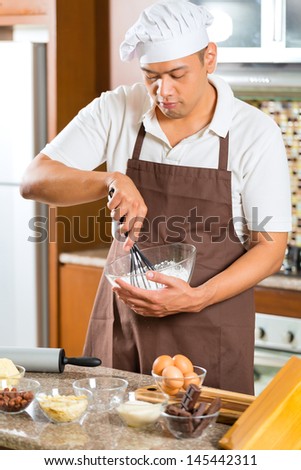 Asian man baking homemade cake in his kitchen for dessert