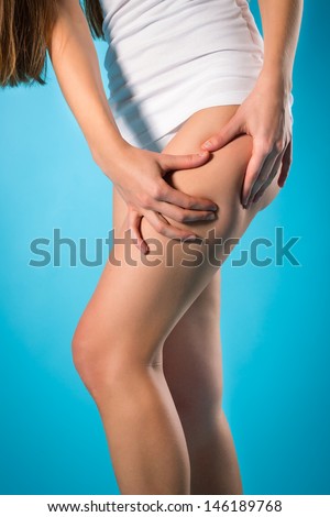 Diet and loosing weight - young woman checking her thigh for cellulite or orange skin
