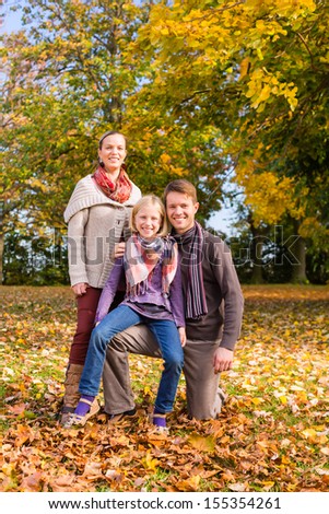 Happy family, Mother, father and daughter or child standing outdoor with colorful leaves and under the trees in autumn or fall