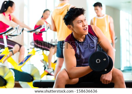 Chinese Asian group of men and woman doing sport exercise or training in fitness gym with barbell and weights for more power