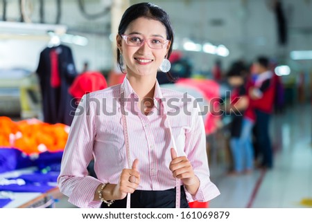 Female Indonesian tailor, dressmaker or designer standing proudly in an Asian textile factory, it is her workplace