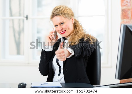 Young lawyer or secretary working in her Office, she sits on the desk and on the telephone is a customer or client