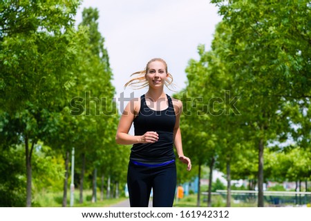 Urban sports - woman running for better fitness in the city park on a cloudy summer day