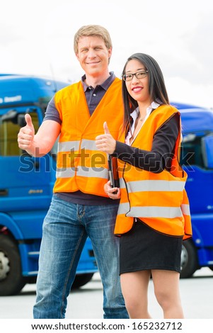 Logistics - proud driver or forwarder and female coworker with tablet computer, in front of trucks and trailers, on a transshipment point, its a good and successful team