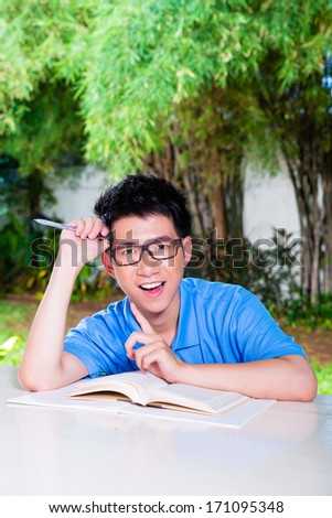 Young Chinese Asian student is successful at home with difficult homework assignment for school next day