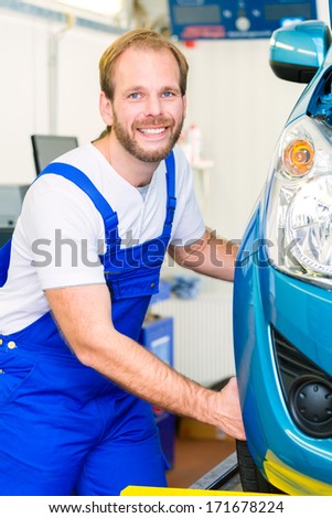 Mechanic in workshop or MOT with car or auto for service inspection
