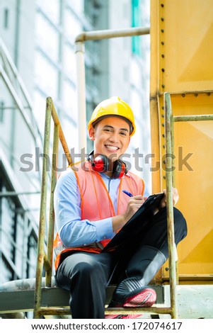Asian Indonesian construction worker with helmet and safety vest on a building or industrial site in Asia