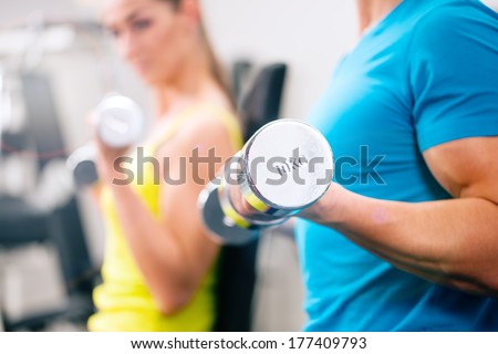 Couple training for fitness in gym with weights