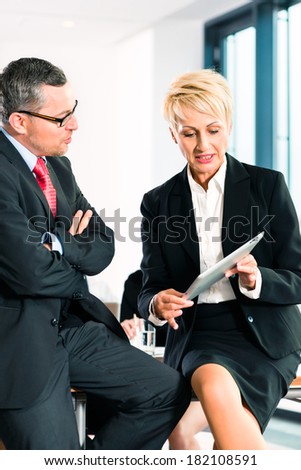 Business - meeting in office, two senior managers are discussing a document on tablet computer