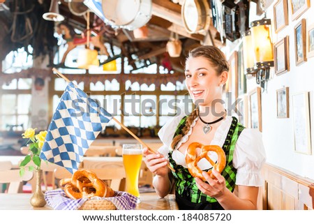 Bavarian woman wearing dirndl drinking beer in German restaurant