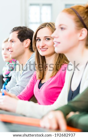 College students making lesson notes in university auditorium