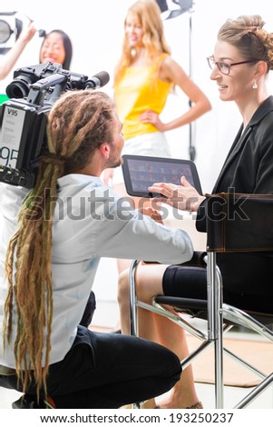Director giving cameraman shoot or scene direction on set of a video production for TV, television or News