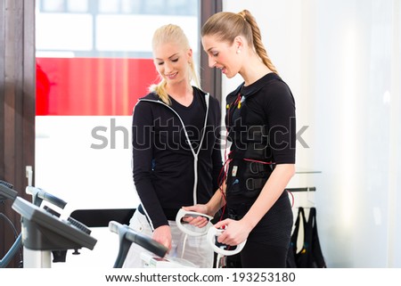 Female coach controlling results after ems electro muscular stimulation training with body fat measuring