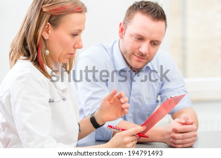 Young doctor sitting with patient in surgery consultation hour at desk