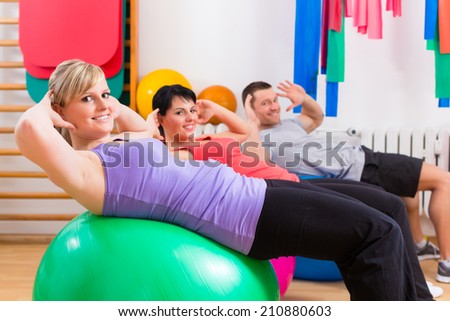 Patients at the physiotherapy doing physical exercises with therapist on training balls