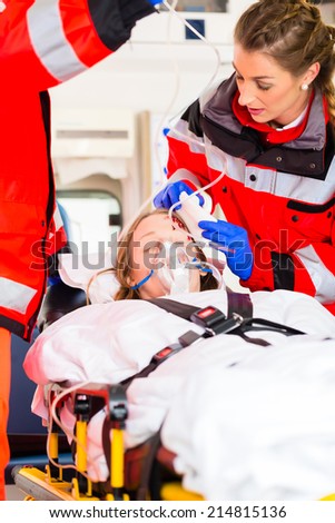 Emergency doctor and nurse or ambulance team transporting accident victim on stretcher