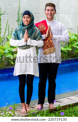 Asian Muslim man and woman welcoming guests wearing traditional dress
