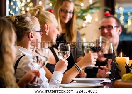 German parents and children toasting with wine and water at Christmas eve dinner