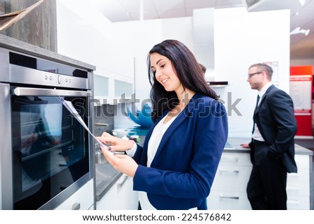 Woman picking oven for domestic kitchen in studio or furniture store