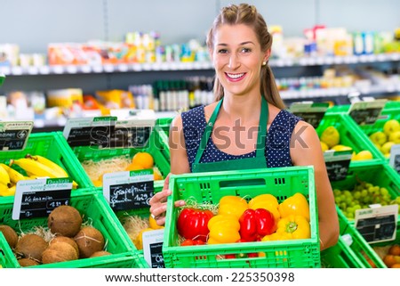 Female organic grocery shop assistant filling up coconuts storage racks in vegetable department