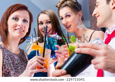 Friends drinking with barkeeper cocktails in fancy night club