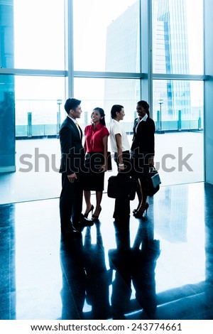 Group of business people standing in lobby or hall, a city skyline in the background
