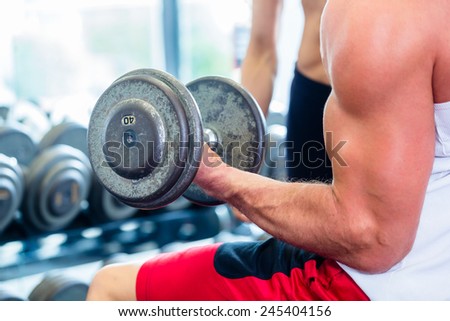 Couple in fitness gym with dumbbells lifting weight as sport, man and woman training together