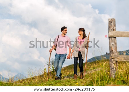 couple of man and woman hiking on mountain summit or alpine grassland in the Bavarian Alps, enjoys the panorama in the leisure time or in vacation