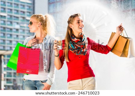 Women shopping in city with bags having coffee and bags in hands