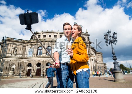 Tourist couple at Semperoper in Dresden taking selfie with phone on stick