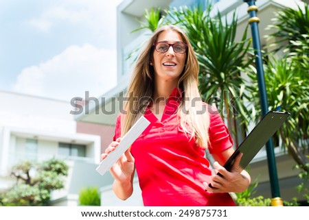 Female Architect with folding rule and clipboard in front of house