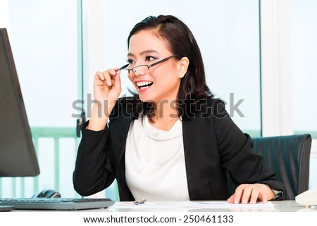 Asian Chinese business woman working in office controlling profit