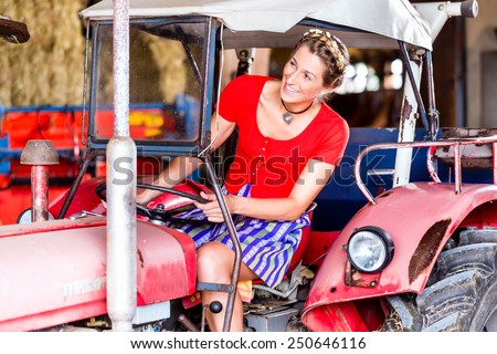 Bavarian woman with Dirndl dress driving tractor