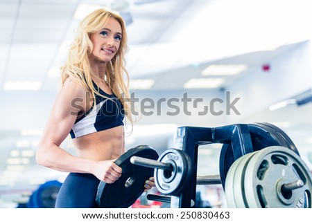 Woman taking weights from stand in fitness gym preparing for training