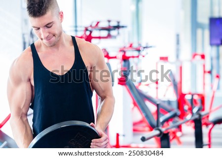 Man taking weights from stand in fitness gym preparing for training