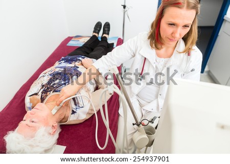 Female doctor testing thyroid of senior patient with surgery ultrasonic device