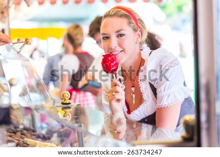 Woman eating candy apple at Oktoberfest wearing Dirndl