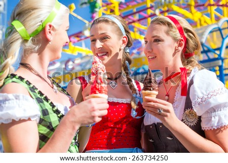 Friends visiting together Bavarian fair in national costume eating sundae ice