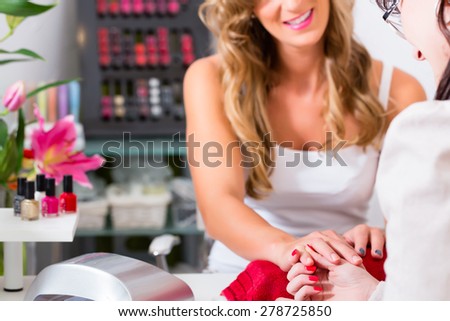 Woman receiving manicure in beauty parlor, her nails being polished