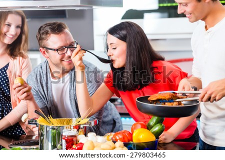 Friends cooking spaghetti and meat in domestic kitchen