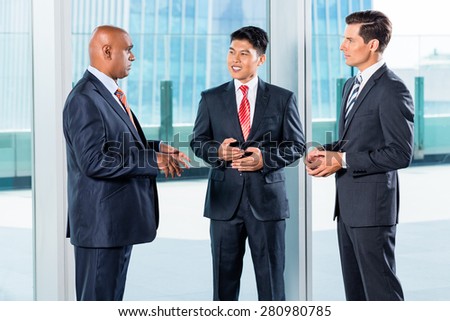 Multi ethnic business team reporting to Indian CEO discussing in front of city skyline